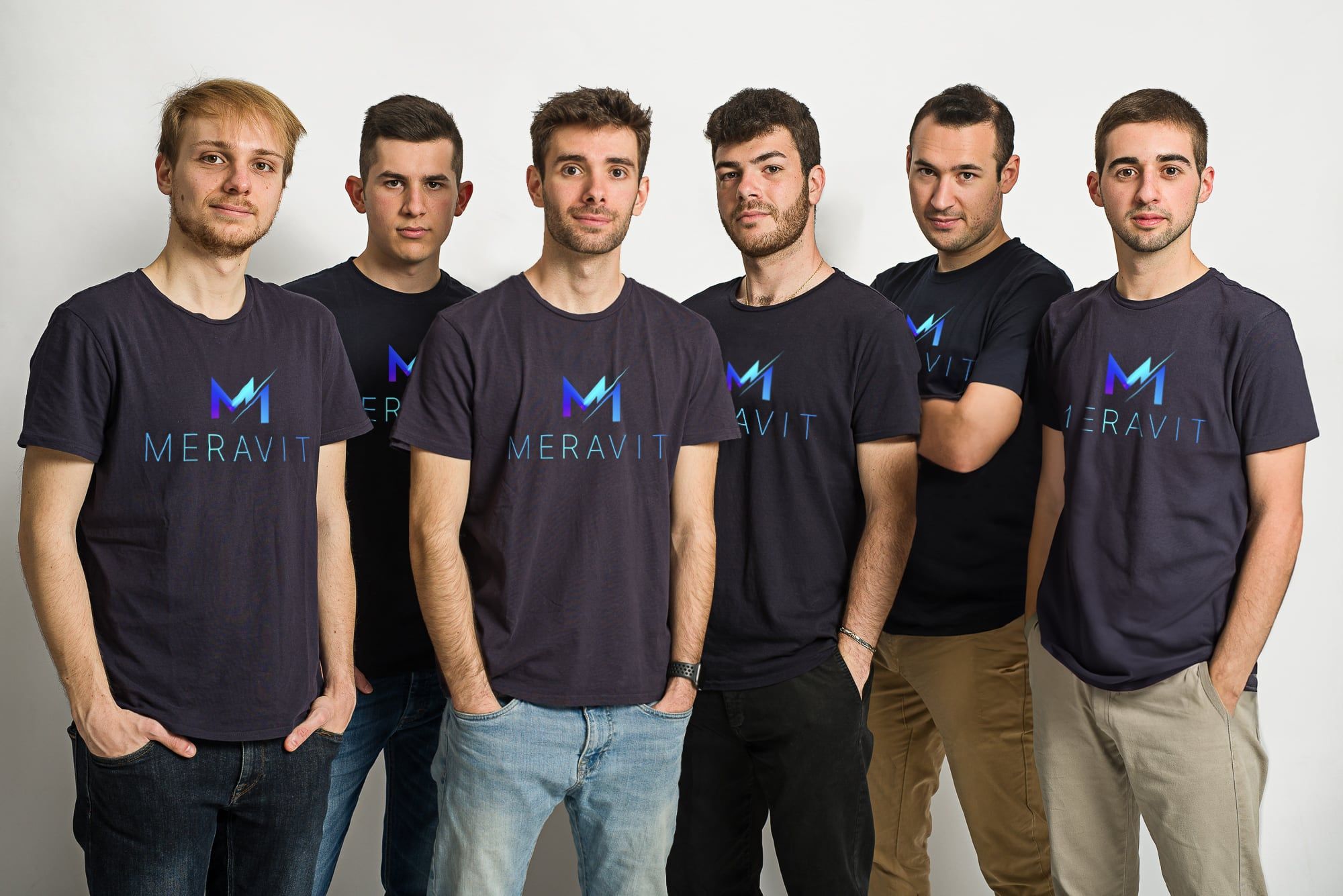 The Meravit team, six people in navy Meravit T-shirts, standing together against a white wall