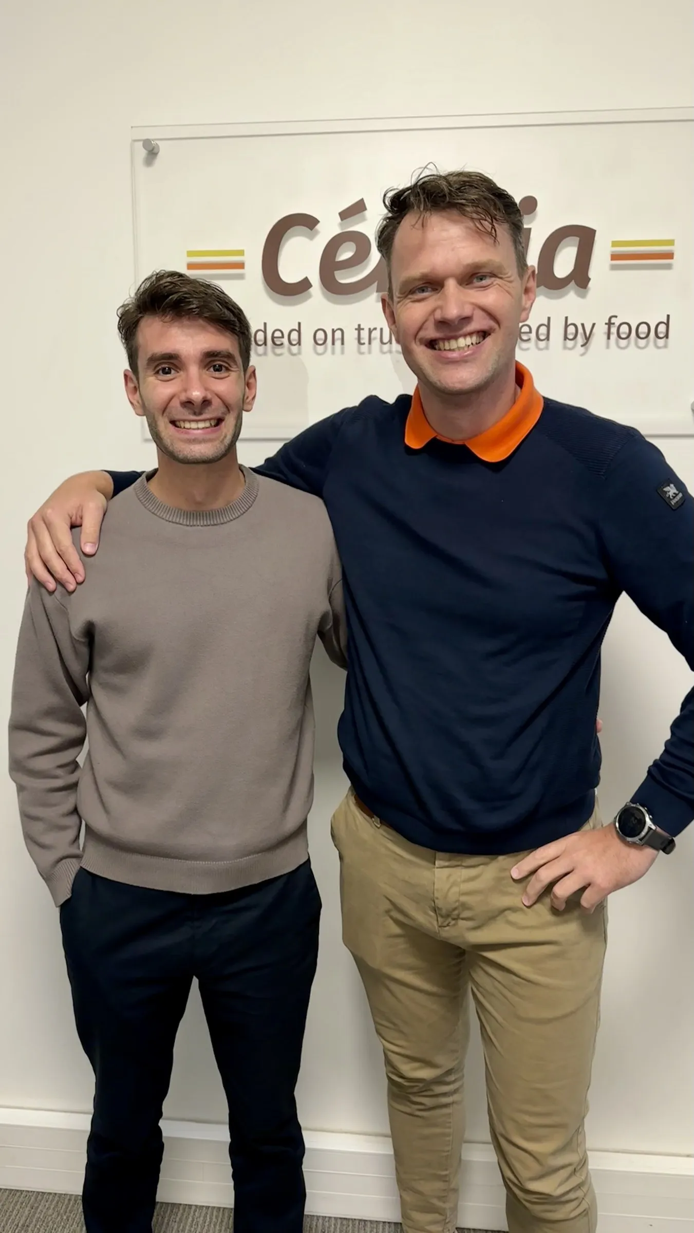 Enrico con un’altra persona del team di Cérélia davanti al logo dell’azienda